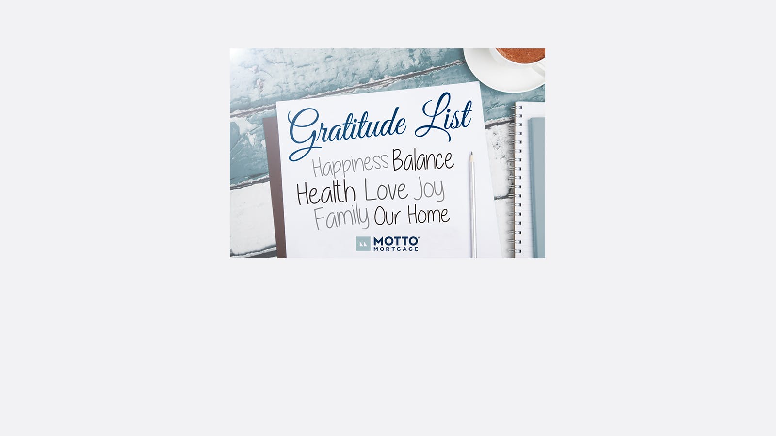 A notepad on a wooden table lists words under Gratitude List: Happiness, Balance, Health, Love, Joy, Family, Our Home. A coffee cup and a spiral notebook are also partially visible.