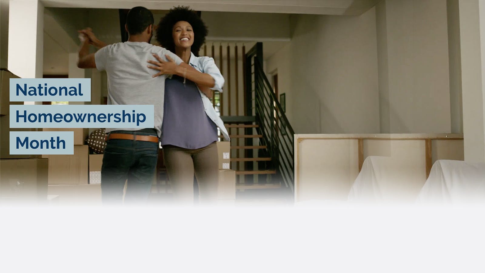 A happy couple dances in their new home surrounded by moving boxes. Text on the left reads: National Homeownership Month.