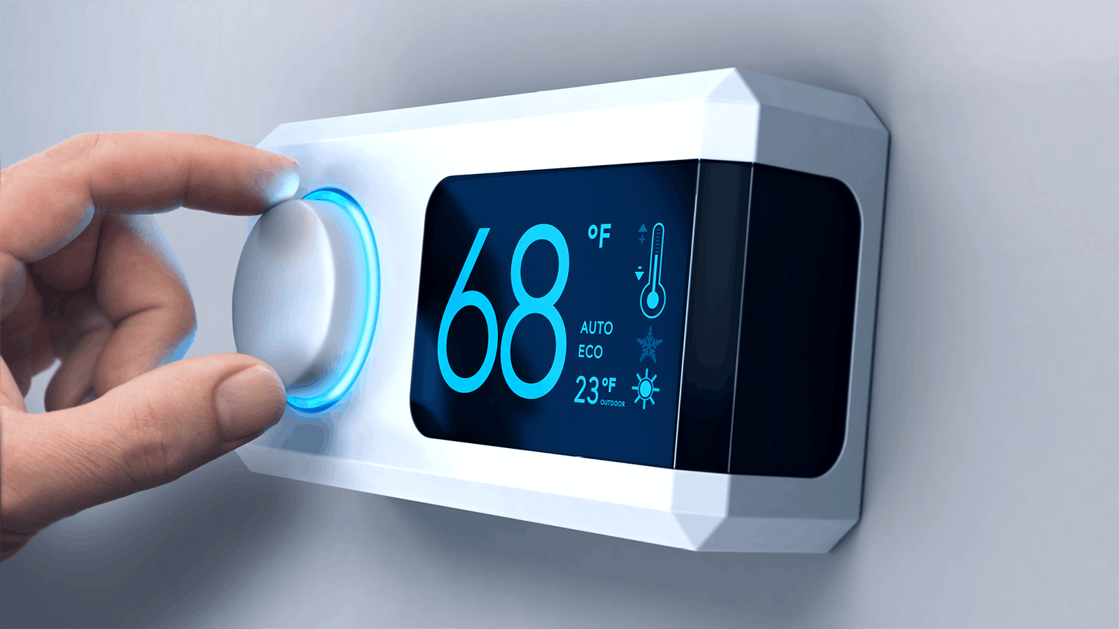 A hand turns the dial of a modern digital thermostat displaying 68°F, with icons for auto and eco modes, a thermometer, and an outside temperature of 23°F on a blue screen.