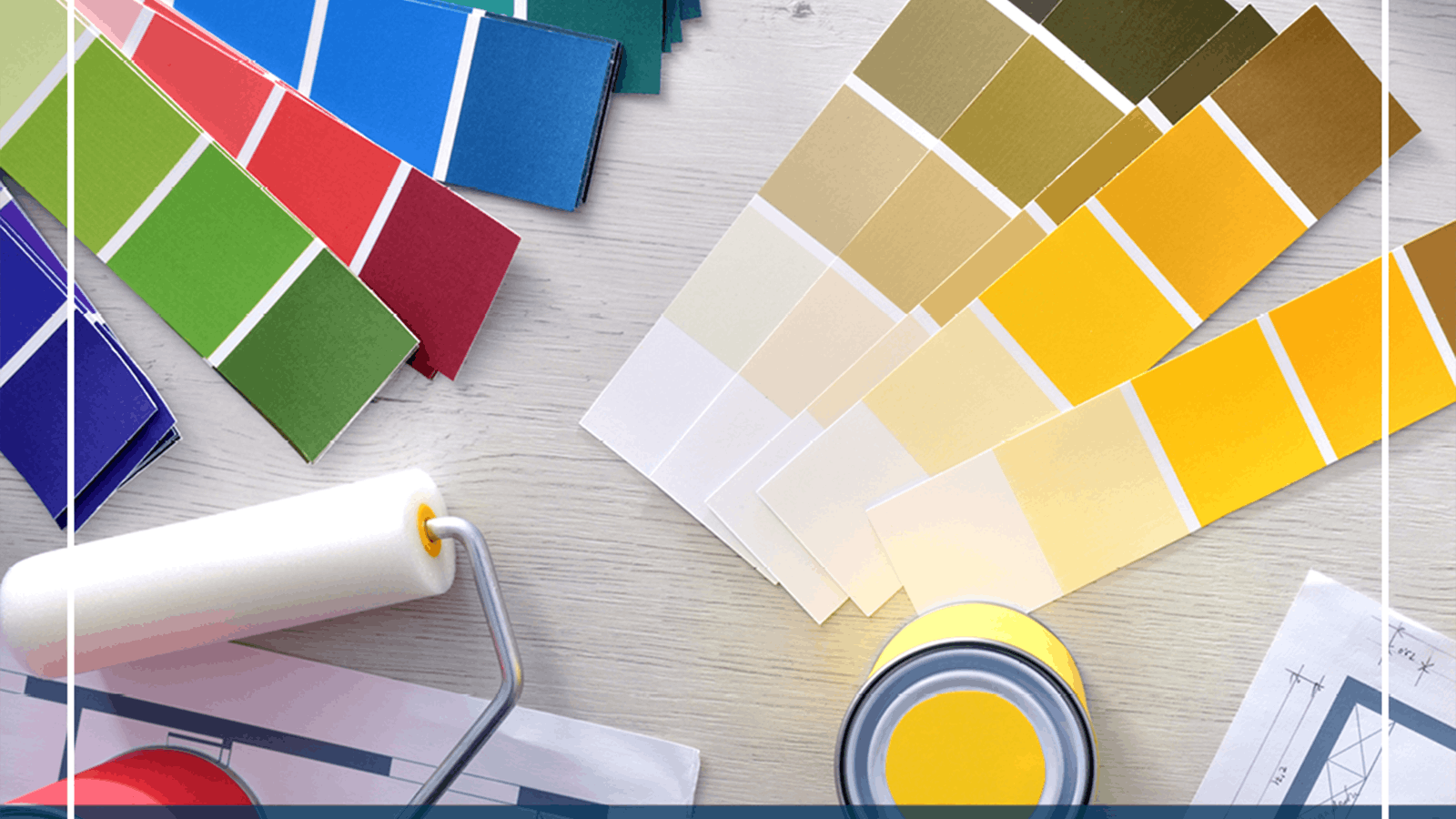 A paint roller, paint can, and several color swatches in green, blue, red, yellow, and neutral tones are arranged on a light wooden surface.