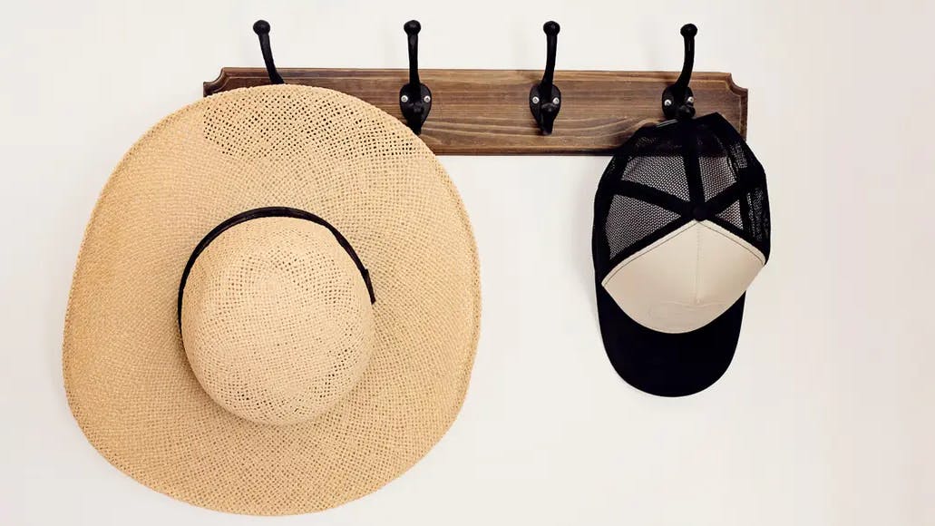 Wall hook with a straw hat and trucker hat hanging from it. (Courtesy of Realtor Magazine)
