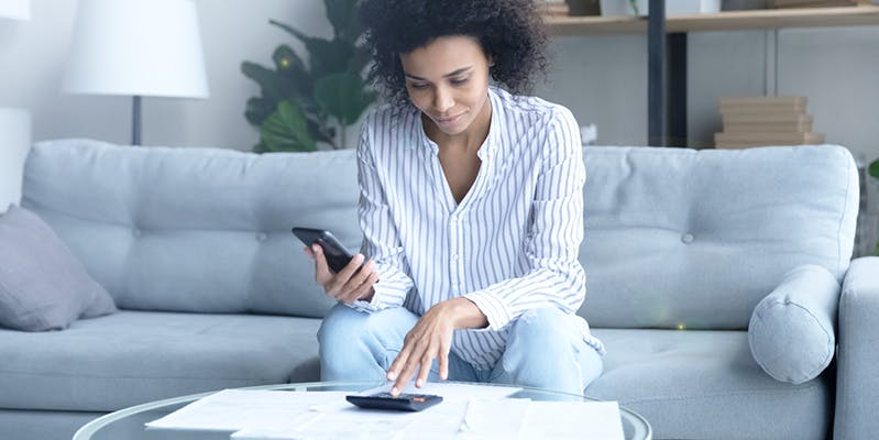 Woman sitting on a couch, using a mortgage payment calculator