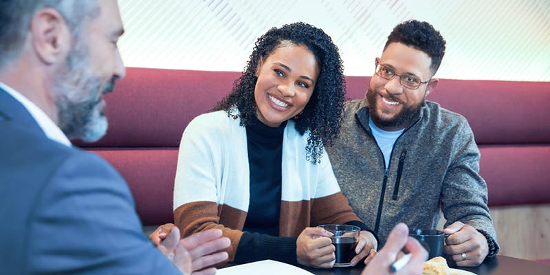 A happy couple speaking with a financial professional about how to manage their personal loan repayments