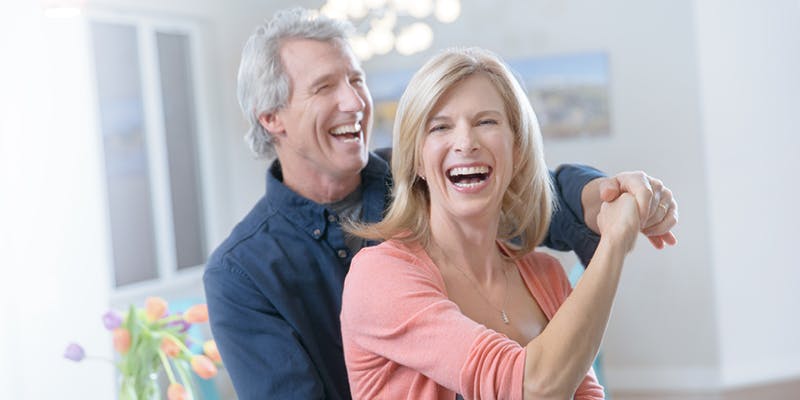 A couple dancing in a living room that features flowers in the Pantone color of the year 2024.