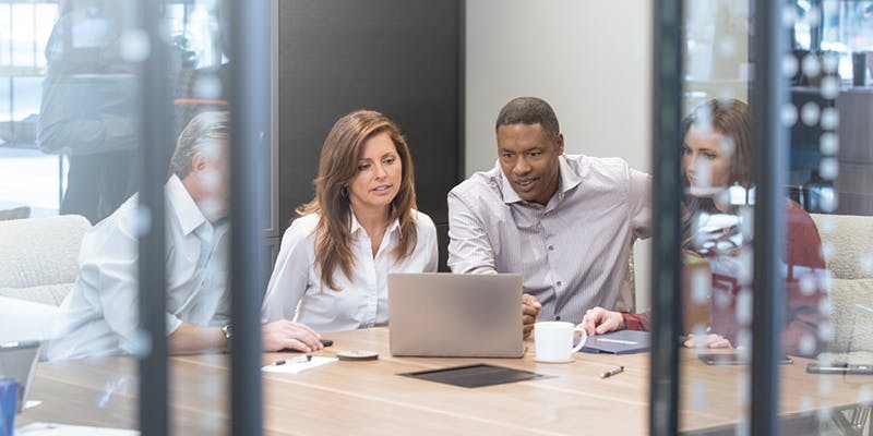 Photo of a couple looking at mortgage market trends for 2024 with a mortgage professional on a laptop