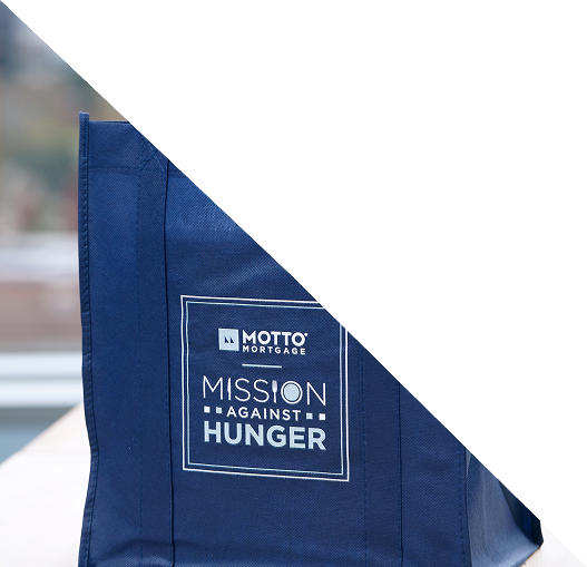 A blue reusable bag with the text Motto Mortgage Mission Against Hunger printed on it, partially covered by a white triangular overlay in the top right corner.